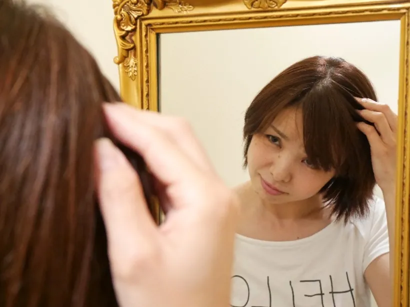 鏡の前で髪と頭皮の悩みを気にする女性